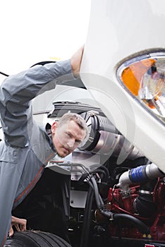 Inspector checking working engine on white big rig semi truck