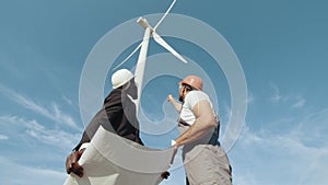 Inspector and engineer are inspecting a project in a wind turbine field that produces electricity. Clean energy concept