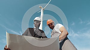 Inspector and engineer are inspecting a project in a wind turbine field that produces electricity. Clean energy concept