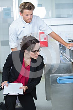 inspector examining food supplies in restaurant kitchen accompanied by chef