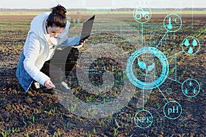 An inspector farmer with a laptop collects data on the field for subsequent analysis of plant growth and identify deficiencies to