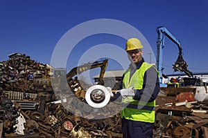 Inspector hold old car rotor on junkyard