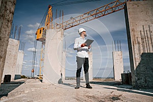 Inspector with notepad is standing on the construction site