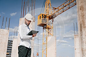 Inspector with notepad is standing on the construction site