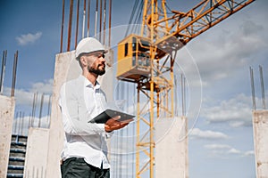 Inspector with notepad is standing on the construction site