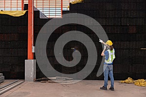 Inspector Pointing to Stack of Steel Bars in a Warehouse