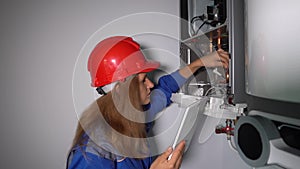 Inspector technician woman inspecting gas boiler heating system with computer