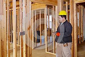 Inspector with yellow hard hat checking electrical wiring inside house