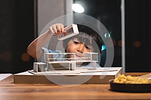 Inspiration kids in occupation, Asian kid playing and concentrating to home model box in the job of parent at office room at night