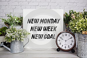 Inspiration quote `New Monday New Week New Goal` text message with artificial plant decoration on wooden background