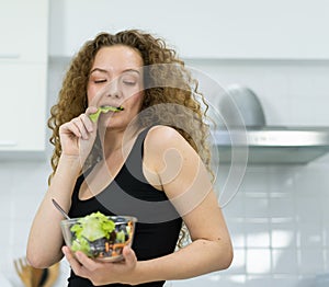 inspiration of smart caucasian woman eating vegetable salad in kitchen with copy space. beautiful caucasian woman cooking healthy