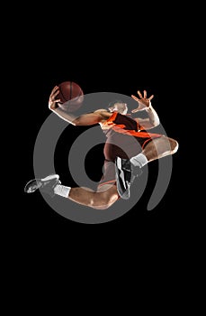 Young professional basketball player in action, motion isolated on black background, look from the bottom. Concept of