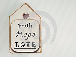 Inspirational concept - faith, hope, love text written on wooden frame background. Stock photo.