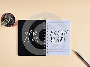 Inspirational Concept - NEW YEAR FRESH START text written on notebook background. Stock photo.