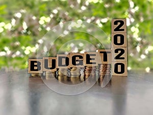 inspirational and conceptual - budget 2020 on wooden blocks with coins stack background