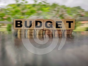 inspirational and conceptual - budget on wooden blocks with coins stack background