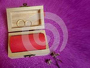 Inspirational image of blank red notepaper inside small wooden box with rings and flower in blurry motion background