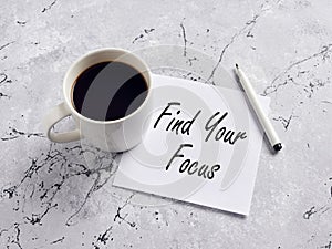 The inspirational message find your focus handwritten on a paper with pen and coffee mug