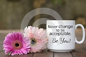 Inspirational message on a coffee cup with soft pink flowers - Never change to be acceptable. Be you. photo