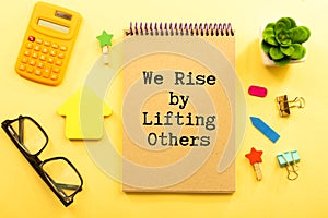 Inspirational and motivation life quote on notepad - We Rise by Lifting Others