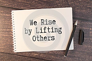 Inspirational and motivation life quote on notepad - We Rise by Lifting Others