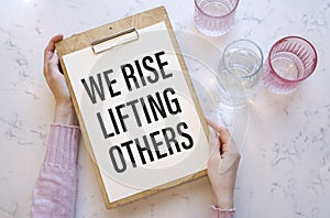 Inspirational and motivation life quote on notepad text we rise lifting others