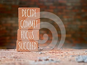 Inspirational and Motivational Concept - DECIDE COMMIT FOCUS SUCCEED text on bricks background. Stock photo.