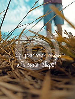 Inspirational motivational quote - Big journeys begin with small steps. With dry grass and blur man\'s feet .