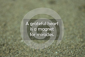 Inspirational motivational quote - A grateful heart is a magnet for miracles. With blurry black sands pattern texture background.