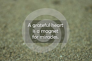 Inspirational motivational quote - A grateful heart is a magnet for miracles. With blurry black sands pattern texture background. photo