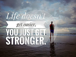 Inspirational motivational quote - Life does not get easier. You just get stronger. Young man standing on beach.