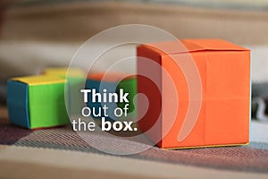 Inspirational  motivational quote - Think out of the box. With one big orange gift box and blur small colorful cubes background.