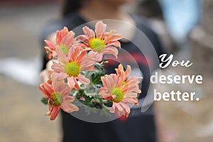 Inspirational motivational quote - You deserve better. With young girl holding and showing beautiful bouquet of peach dahlia.