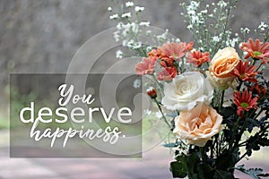 Inspirational motivational quote - You deserve happiness. With bouquet of roses and daisy gerbera flowers background