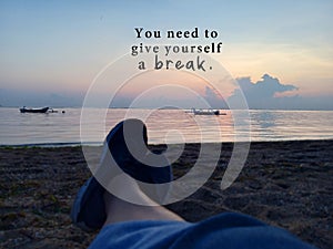 Inspirational motivational quote - You need to give yourself a break. With blurry image of young woman legs sitting alone on sands