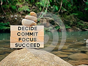 Inspirational and motivational words of decide commit focus succeed on wooden blocks with blurred nature background.