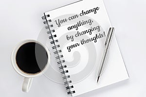 Inspirational motivational words - You can change anything, by changing your thoughts. On book with pen, morning coffee on white.