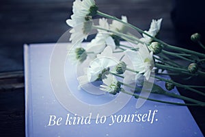 Inspirational quote - Be kind to yourself. Self love and care concept. On vintage background of white daisy flowers bouquet.