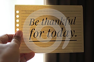 Inspirational quote - Be thankful for today. With young woman holding paper notes in hand, showing positive emotion.