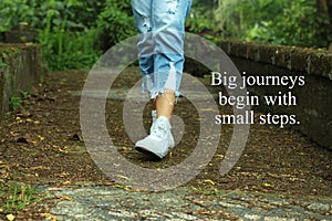 Inspirational quote- Big journeys begin with small steps. With feet of young woman walking surrounding with fresh green nature