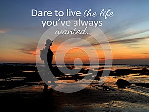 Inspirational quote - Dare to live the life you`ve always wanted. With silhouette of a adventurous woman standing alone on beach.