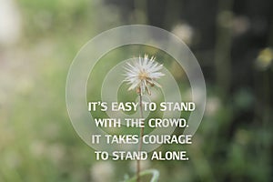 Inspirational quote - It is easy to stand with the crowd. It takes courage to stand alone. With white wild flower & green meadow