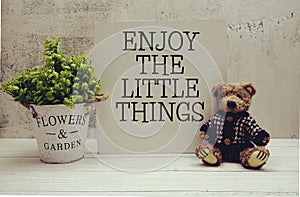 Inspirational quote Enjoy the Little Things text message written on white wooden board