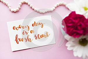 Inspirational quote Every day is a fresh start written in calligraphy style with watercolor. Composition on a pink background. Fla