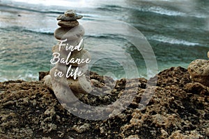 Inspirational quote - Find balance in life on background of rock balancing and calm wave water in the beach. Life balance.