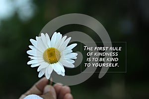 Inspirational quote - The first rule of kindness is to be kind to yourself. Self love care, healing concept with flower in hand.