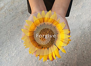 Inspirational quote - Forgive. With background of sunflower blossom in an open hands. Forgiving words of wisdom concept.