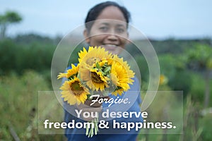 Inspirational quote - Forgive. You deserve freedom and happiness. With young woman hand holding and showing bouquet of sunflowers.