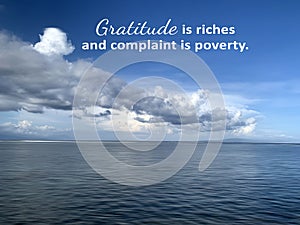 Inspirational quote - Gratitude is riches and complaint is poverty. On nature landscape background of bright blue sky with clouds