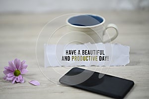 Inspirational quote - Have a beautiful and productive day. With morning a cup of coffee, black smartphone and purple daisy flower